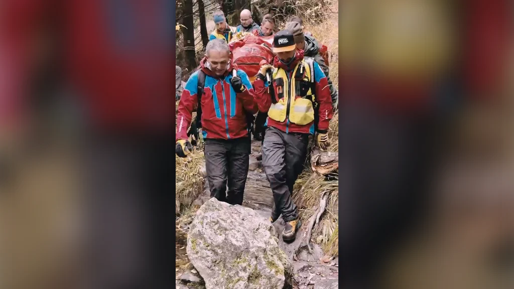 Horští záchranáři nesou na nosítkách zraněnou turistku po kamenité stezce v údolí Bílé Opavy.