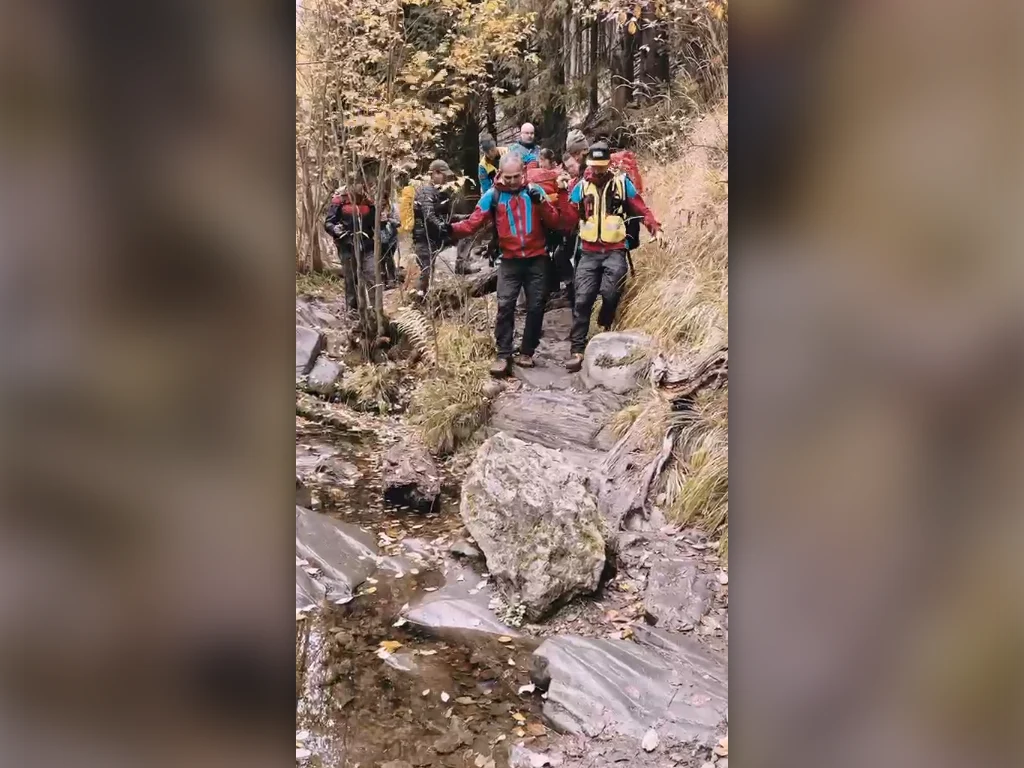 2026-10-19-ma-bila-opava-nahled (4) Horští záchranáři nesou na nosítkách zraněnou turistku po kamenité stezce v údolí Bílé Opavy.