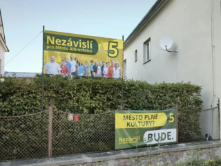 Bannery Nezávislých pro Město Albrechtice na plotě na náměstí ČSA. Spodní visel od 21. srpna, horní od 15. září. Foto: redakce